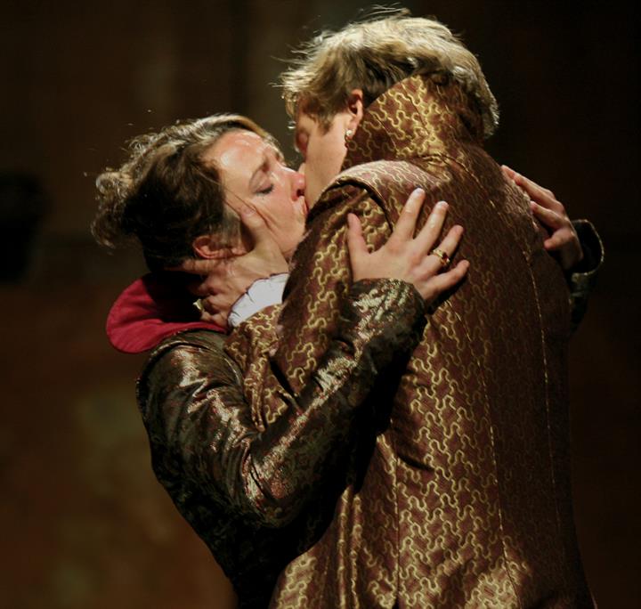 A man and woman kiss on stage